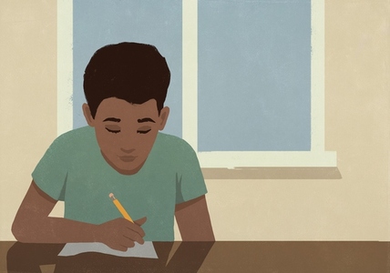 Focused schoolboy doing homework in classroom by window