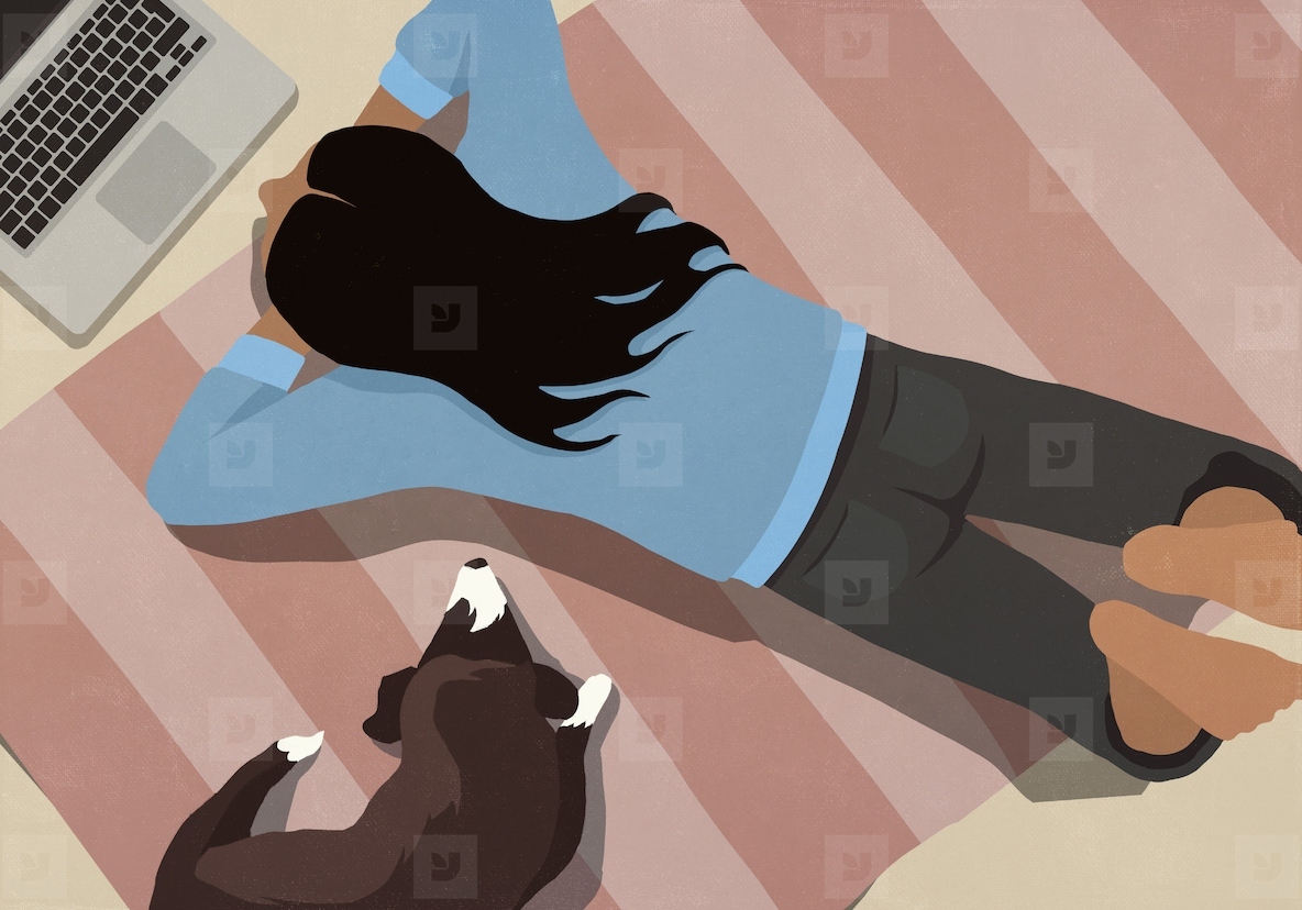 View from above of dog laying next to woman using laptop on striped rug on floor at home