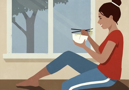 Happy woman eating Vietnamese pho noodles from bowl with chopsticks by window at home