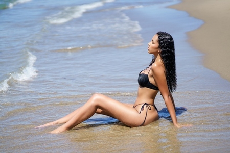 A Relaxing Beach Moment A Model Fully Enjoys the Gentle Waves and the Sunlit Coastline