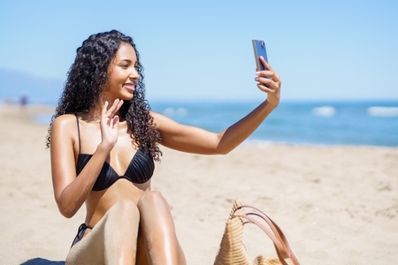 A Young Woman Happily Enjoying a Beautiful Sunny Day While Taking a Fun Selfie at the Beach
