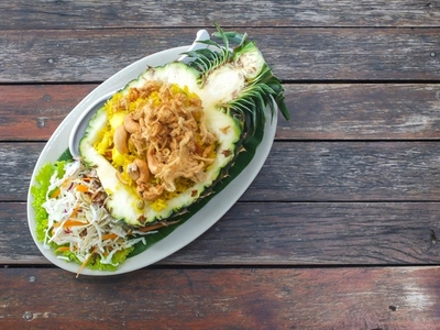 Thai style pineapple fried rice served in a pineapple on a woode Thai style pineapple fried rice served in a pineapple on a woode