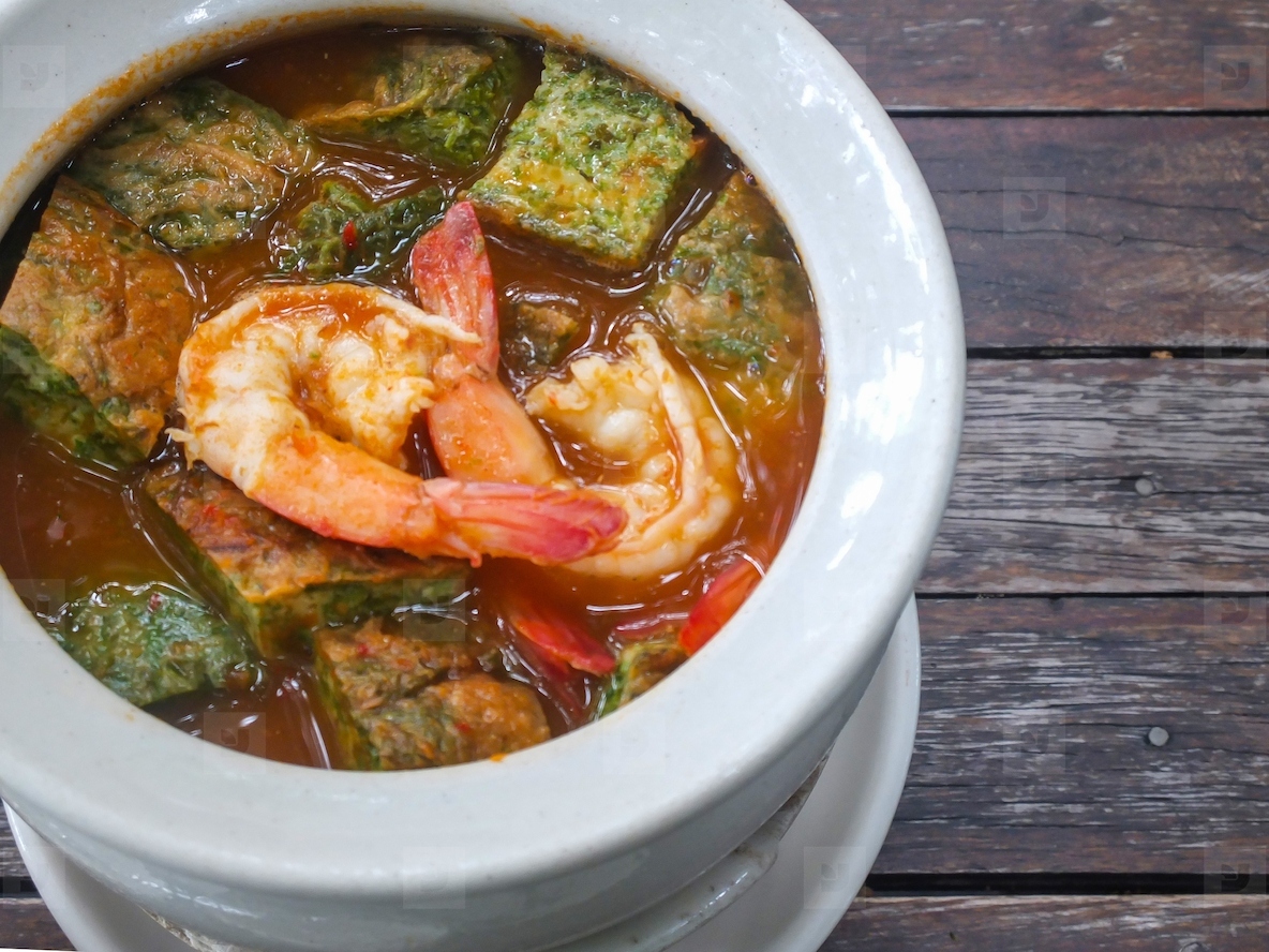 Thai food Cha om egg curry with shrimp in a white bowl on a woo