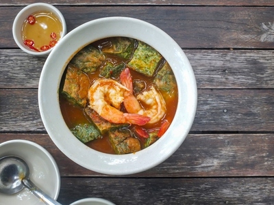 Thai food Cha om egg curry with shrimp in a white bowl on a woo