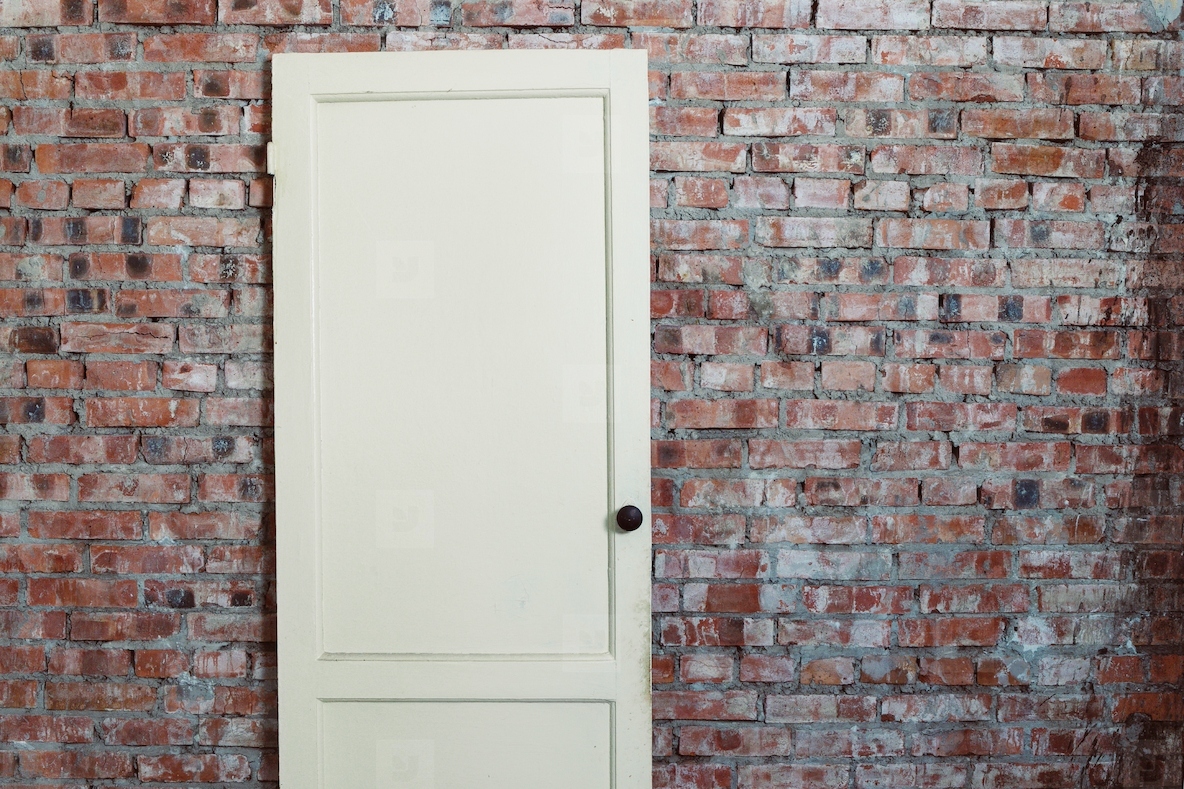 Vintage wooden door with knob in a rustic red brick wall Minimal architecture background and conceptual symbol of opportunity mystery choice and hidden secrets