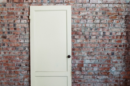 Vintage wooden door with knob in a rustic red brick wall  Minimal architecture background and conceptual symbol of opportunity  mystery  choice  and hidden secrets