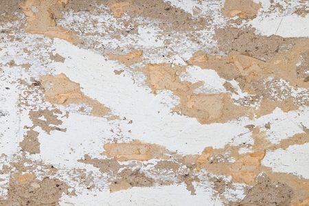Old weathered wall surface with peeling white paint and exposed rough plaster texture  Rustic grunge background with cracked paint  chipped plaster  and distressed vintage look  Perfect for use in des