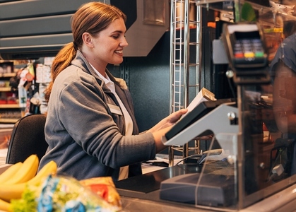 Side view of a cheerful cashier working in a supermarket