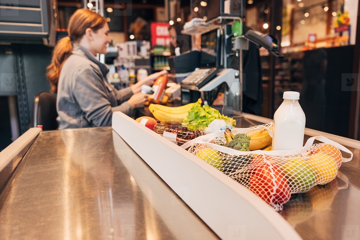 Products in a grocery store on the packaging board and a woman cashier