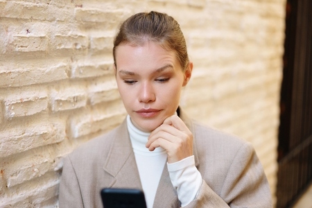 A young woman is deeply engaged with her smartphone while in an urban city setting A young woman is deeply engaged with her smartphone while in an urban city setting