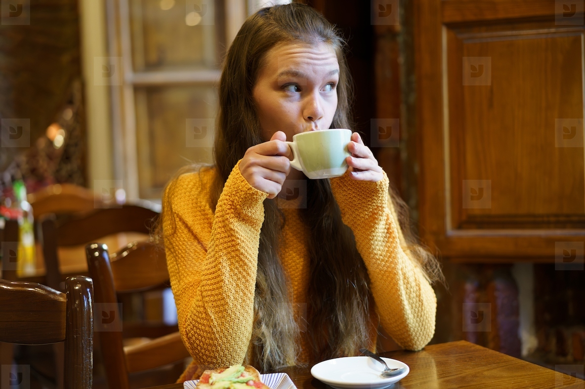 A young woman enjoys a warm drink in a cozy cafe ideal for relaxing and socializing