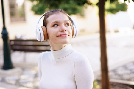 A young woman  carefree and charming  is enjoying music outdoors while wearing her headphones