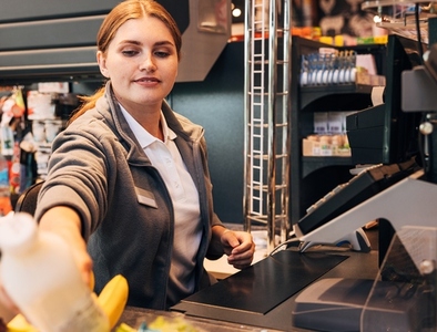 Young woman cashier working at counter  Female employee in a grocery store working at checkout
