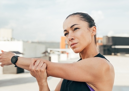 Close up high detailed portrait of a young sportswoman stretching her arm