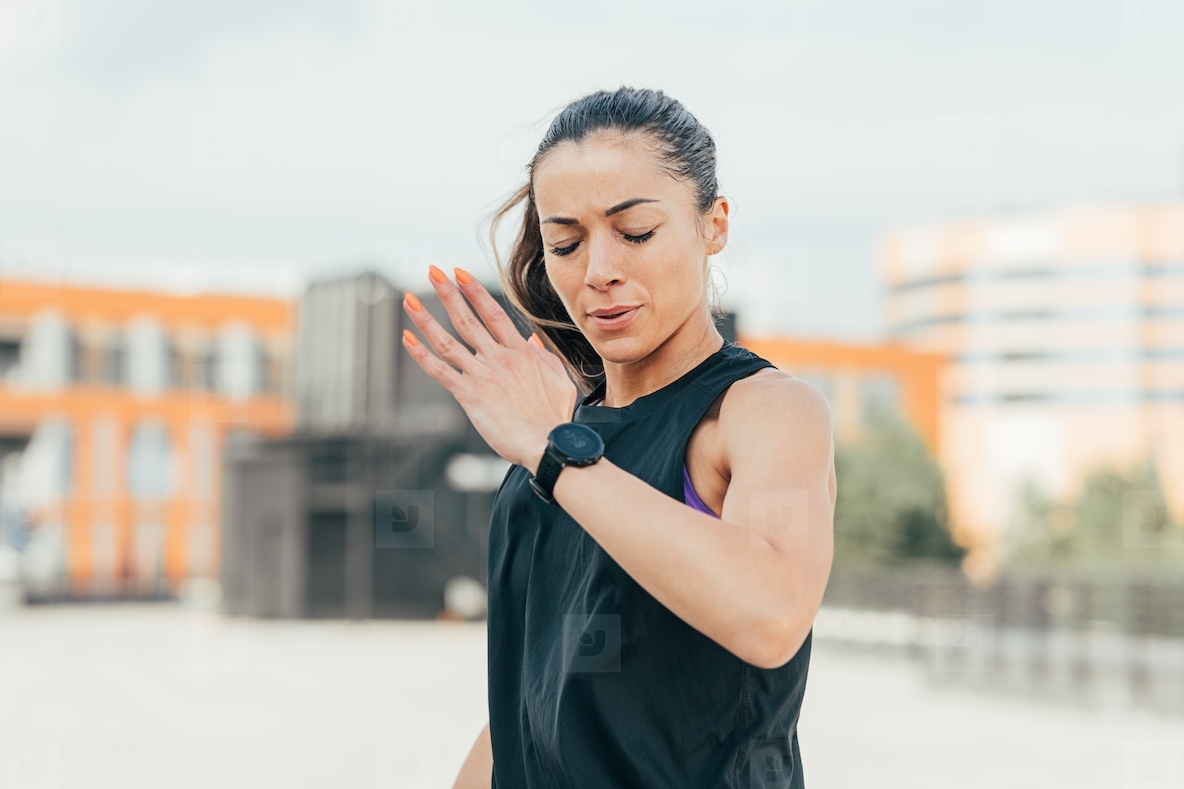 Woman in sportswear is warming up before an outdoor workout running in one place with closed eyes