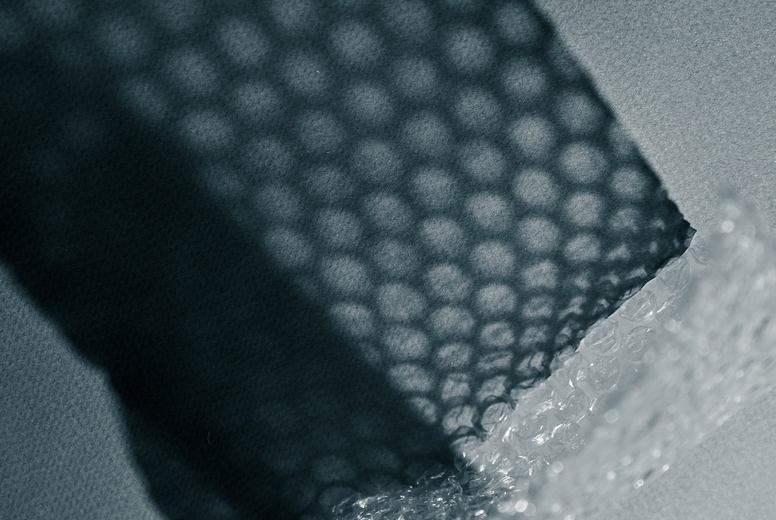Close up of bubble wrap casting geometric shadows on a surface. Abstract minimal texture in monochrome light.