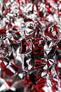 Shiny crumpled foil with silver and red reflections creating a metallic abstract design  Futuristic texture with chrome surface and cyberpunk background style