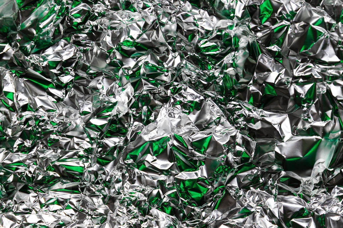 Crumpled foil with silver and green reflections metallic abstract style futuristic texture chrome surface and cyberpunk pattern