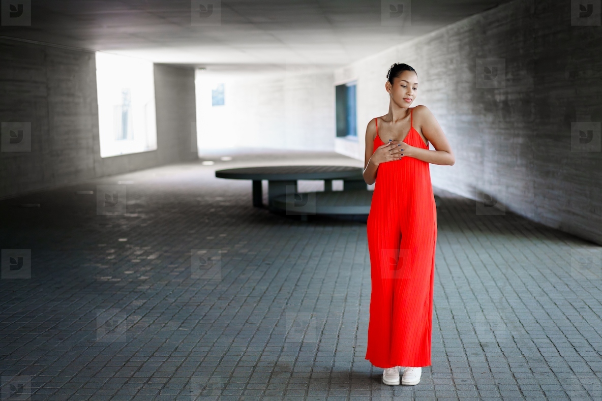 An Elegant Woman Dressed in a Striking Red Dress Posing Gracefully in a Modern Architectural Space