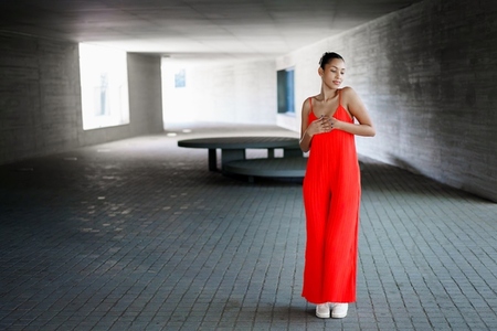 An Elegant Woman Dressed in a Striking Red Dress Posing Gracefully in a Modern Architectural Space