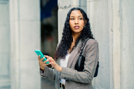 A Stylish Young Woman Engaging with Her Smartphone While in an Urban City Setting A Stylish Young Woman Engaging with Her Smartphone While in an Urban City Setting