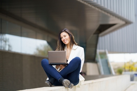 A Young Woman Engaged in Working Remotely on Her Laptop While Enjoying the Outdoors