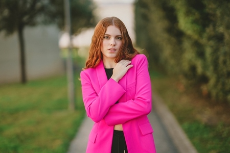 A Chic Young Woman is Posing Outdoors in a Bright Pink Blazer Radiating Confidence and Style A Chic Young Woman is Posing Outdoors in a Bright Pink Blazer Radiating Confidence and Style