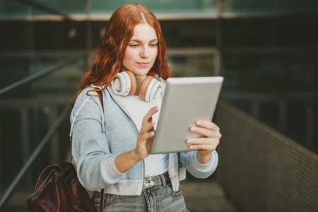A young woman engages with her tablet in a lively city  showcasing a trendy  techsavvy life