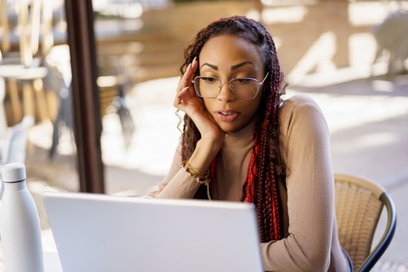 A Focused Young Woman Engaged in Her Work on a Laptop Inside a Modern Cafe Space