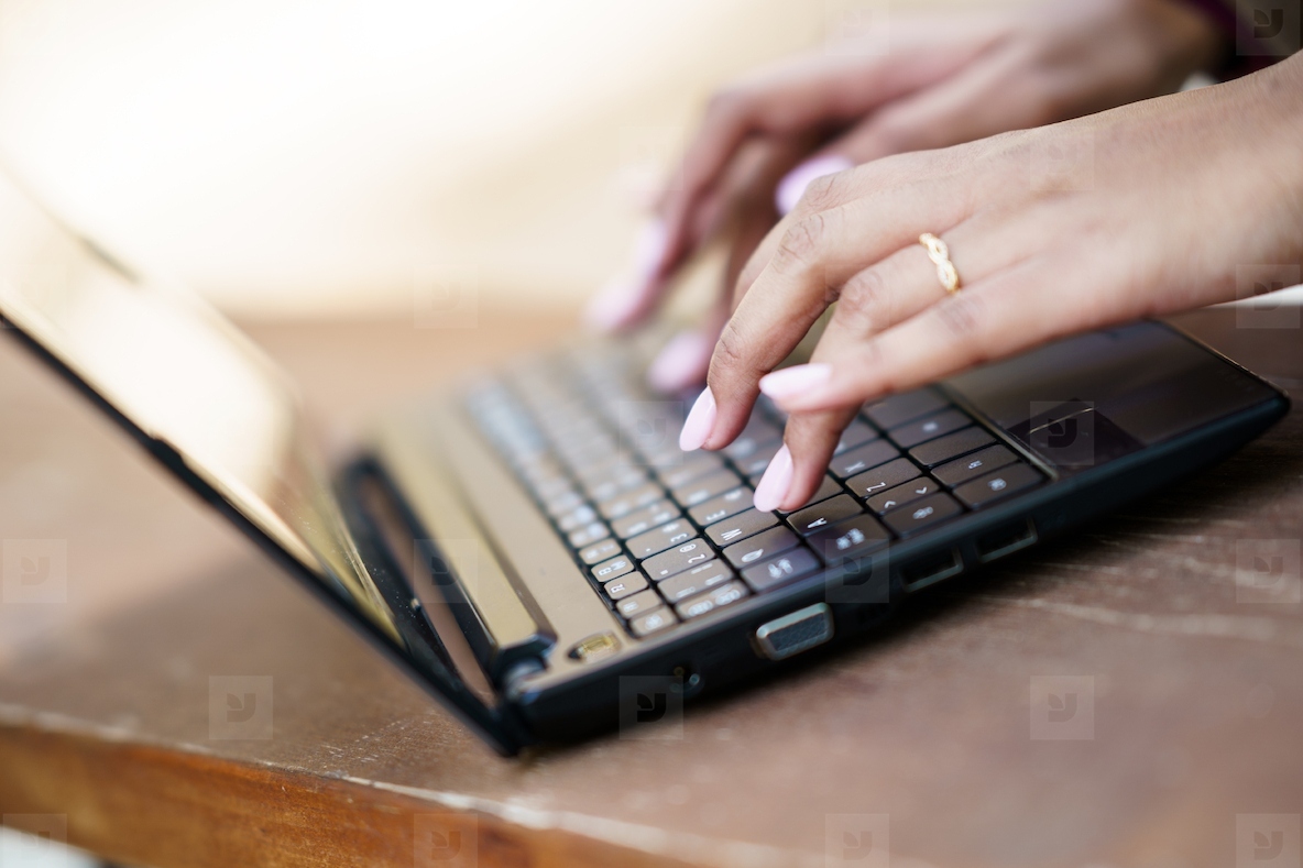 A Closeup Image of Hands Actively Typing on a Laptop Keyboard Within a Cozy Workspace Setting
