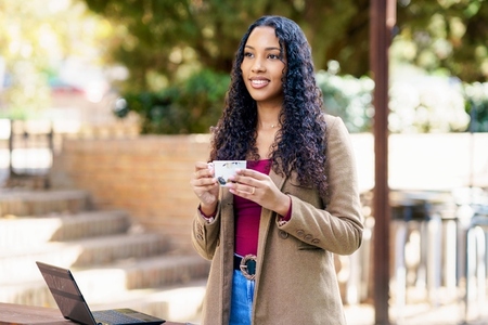 A young woman enjoys coffee and works on her laptop outside  embracing inspiration
