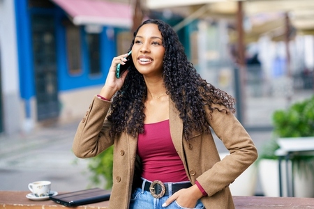 A Young Woman Engaged in a Conversation on the Phone While Seated in an Urban Cafe Setting A Young Woman Engaged in a Conversation on the Phone While Seated in an Urban Cafe Setting