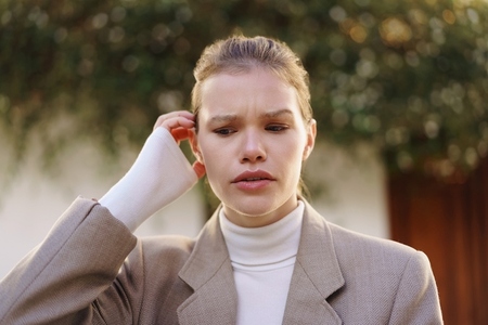 A Woman in Fashionable Attire with a Bandaged Arm Outdoors  Deep in Thoughtful Reflection