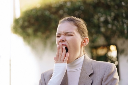 A Yawning Female in Stylish and Contemporary Outerwear Reflects Morning Weariness and Fatigue