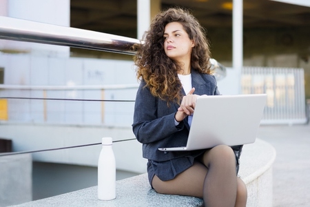 A Professional Woman Engaged in Work Outside While Using Her Laptop with Confidence and Style