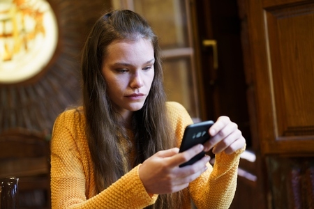 A young woman is using her smartphone while sitting in a cozy cafe  enjoying her time