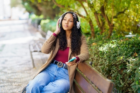 A Young Woman is Enjoying Music in a Relaxing Park Setting Filled with Beautiful Nature