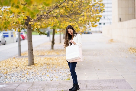 An Autumn Stroll A Graceful Woman Dressed in a Chic White Blazer Carrying a Shopping Bag