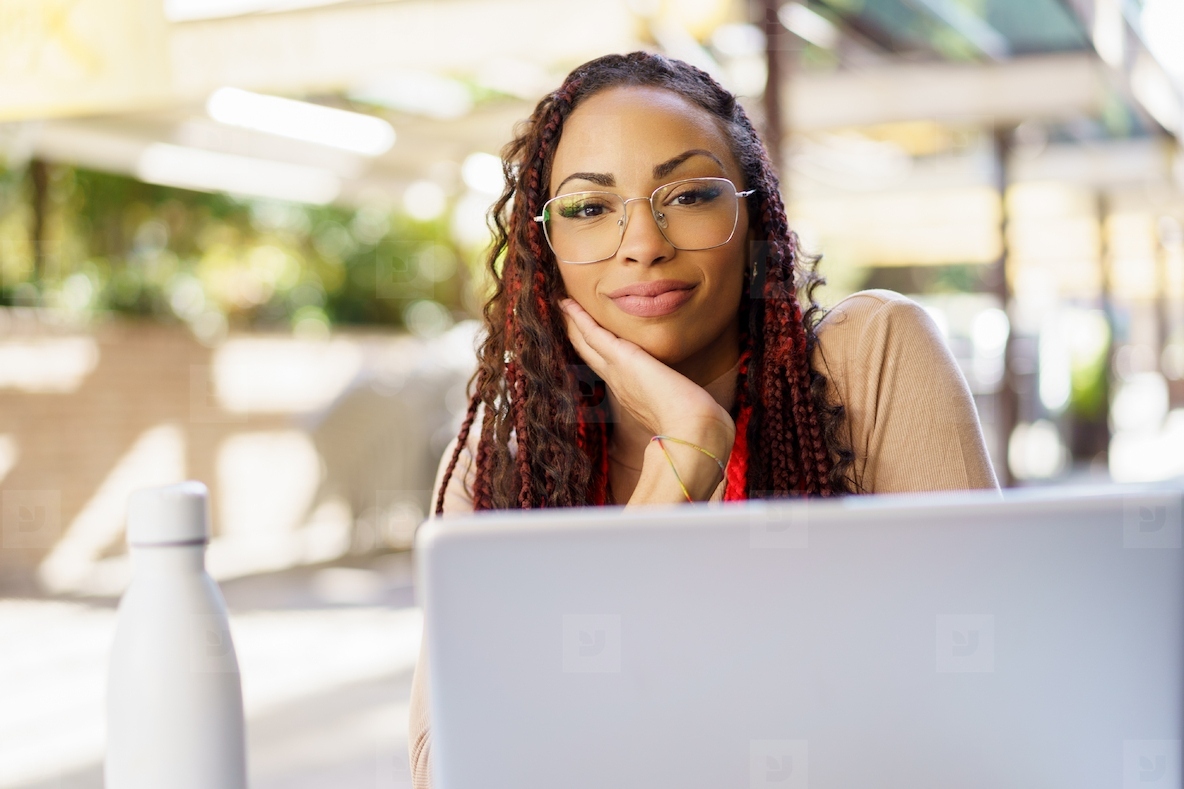 A Thoughtful Woman Engaged in Work on Her Laptop While at an Outdoor Cafe Setting