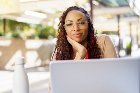 A Thoughtful Woman Engaged in Work on Her Laptop While at an Outdoor Cafe Setting