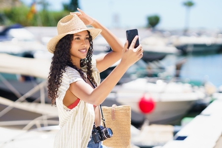A cheerful young woman takes a selfie at a vibrant marina on a bright sunny day A cheerful young woman takes a selfie at a vibrant marina on a bright sunny day