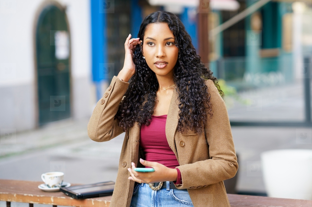 A young woman with stylish curly hair is happily engaged in an animated phone conversation