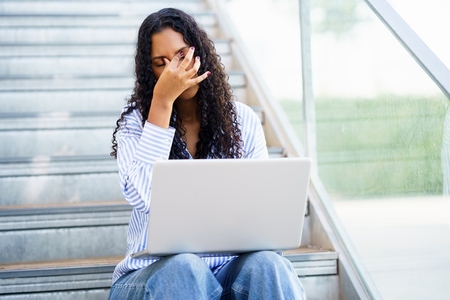 A woman experiencing stress works on her laptop in a modern stylish indoor setting A woman experiencing stress works on her laptop in a modern stylish indoor setting