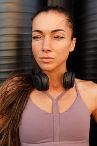 Close up high detail portrait of a young sportswoman with wireless headphones looking away outdoors
