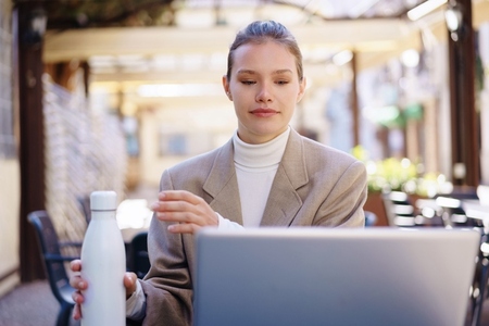 A Young Professional Actively Engaged in Work with Their Laptop and a Water Bottle Nearby