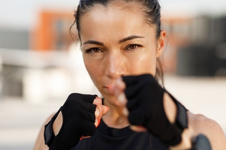 Close up high detailed portrait of a young sportswoman standing in a battle pose and looking at camera
