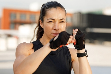 Portrait of a young female practicing shadow boxing outdoors  standing in a battle pose  wearing gloves
