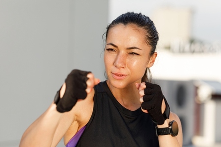 Woman in a fight pose with her fists ready practicing shadow boxing outdoors Portrait of a young sportswoman with perfect skin
