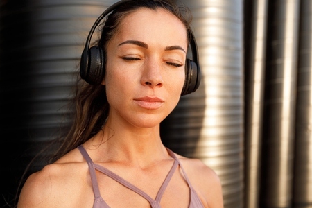 Close up high detailed portrait of a young woman during a workout break  Fitness female with closed eyes and clean skin enjoying music