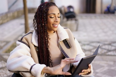 A Young Woman Happily Enjoying EReading Outdoors with a Modern Tablet in the Park